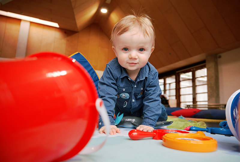 A small child looks at the camera, surrounded by toys.