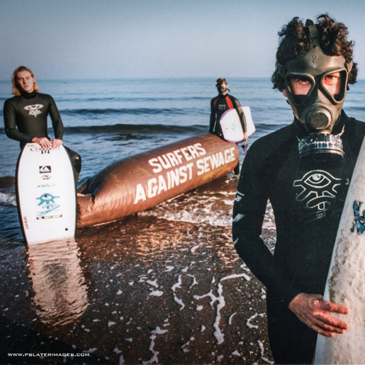 Chris Hines SAS Campaigner holding an SAS branded surfboard and wearing a wetsuit.