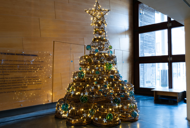 A festive Christmas Tree made of willow lobsters, with glass buoy decorations and twinkling lights.