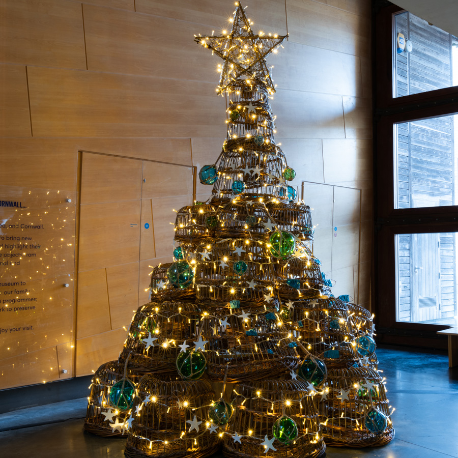 A festive Christmas Tree made of willow lobsters, with glass buoy decorations and twinkling lights.