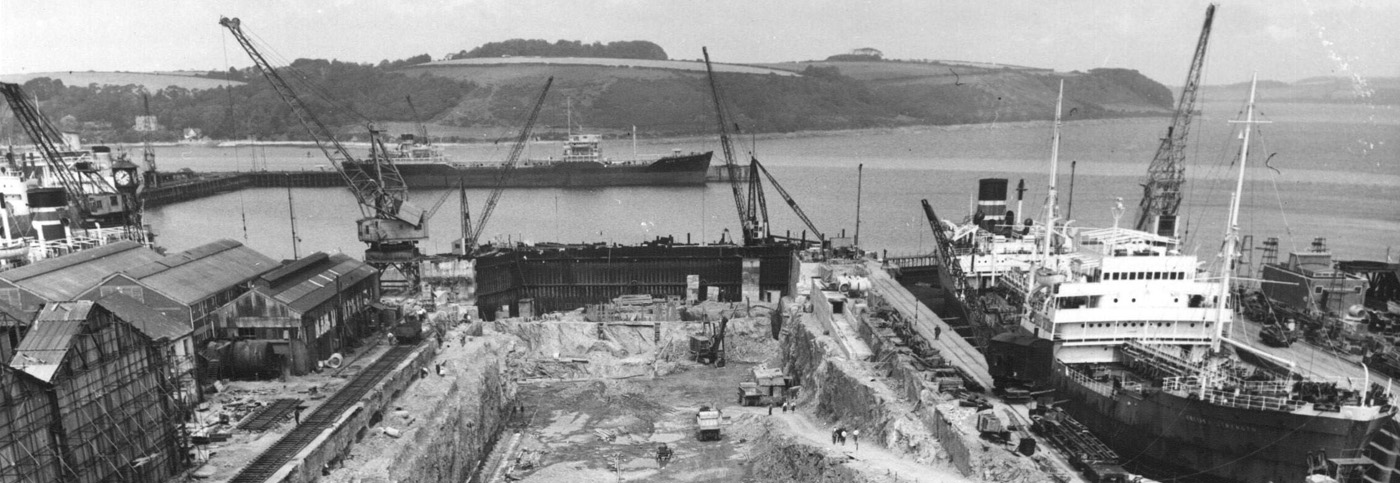 A black and white photograph showing a dry dock under construction.