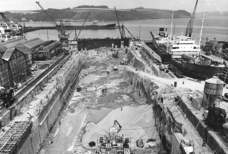 A black and white photograph showing a dry dock under construction.