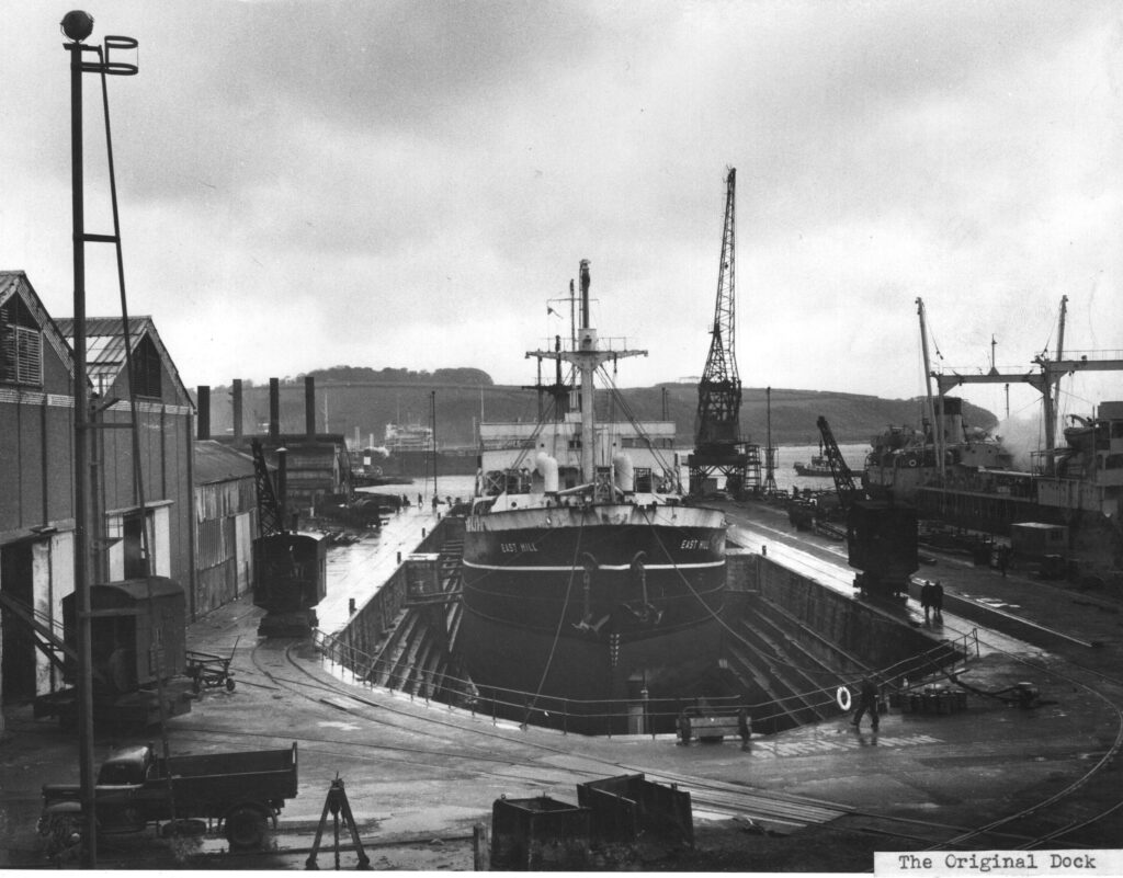 A black & white photograph that shows the original No 2 Dry Dock with a large ship held in the dry dock with timber side shores.