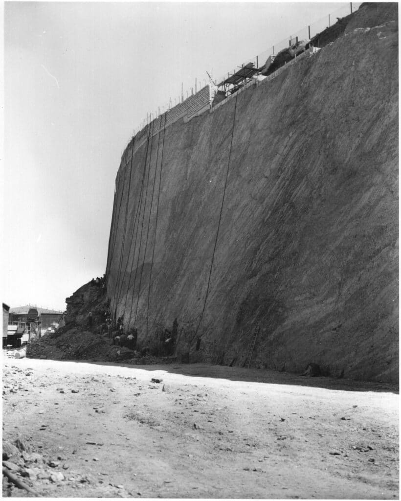 A black & white photograph showing Castle Drive cliff face excavation in progress. 