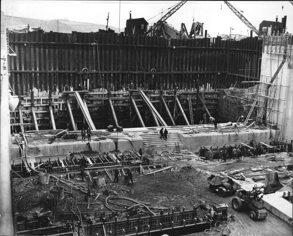 A black and white photograph showing construction progress on building the dam.