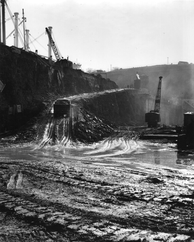 A black and white photograph showing an access ramp constructed on one side of the Dock surrounded by cranes.