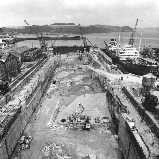 A black and white photograph showing a dry dock under construction.