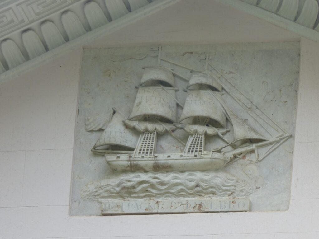 A relief sculpture of a sailing ship on the side of a house.