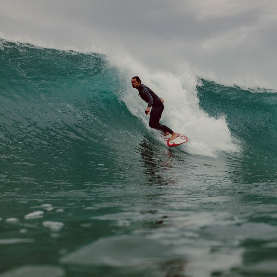 A photograph of a surfer, wearing a wetsuit, surfing a wave.