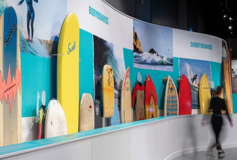 A photograph of an exhibition display of colourful surfboards.