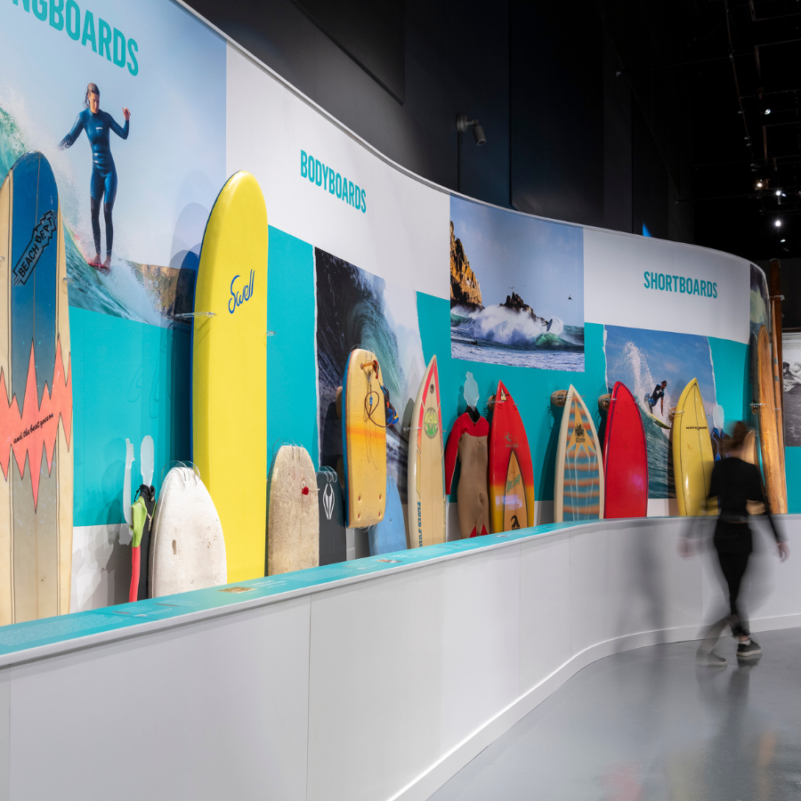 A photograph of an exhibition display of colourful surfboards.