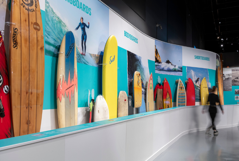 A photograph of an exhibition display of colourful surfboards.