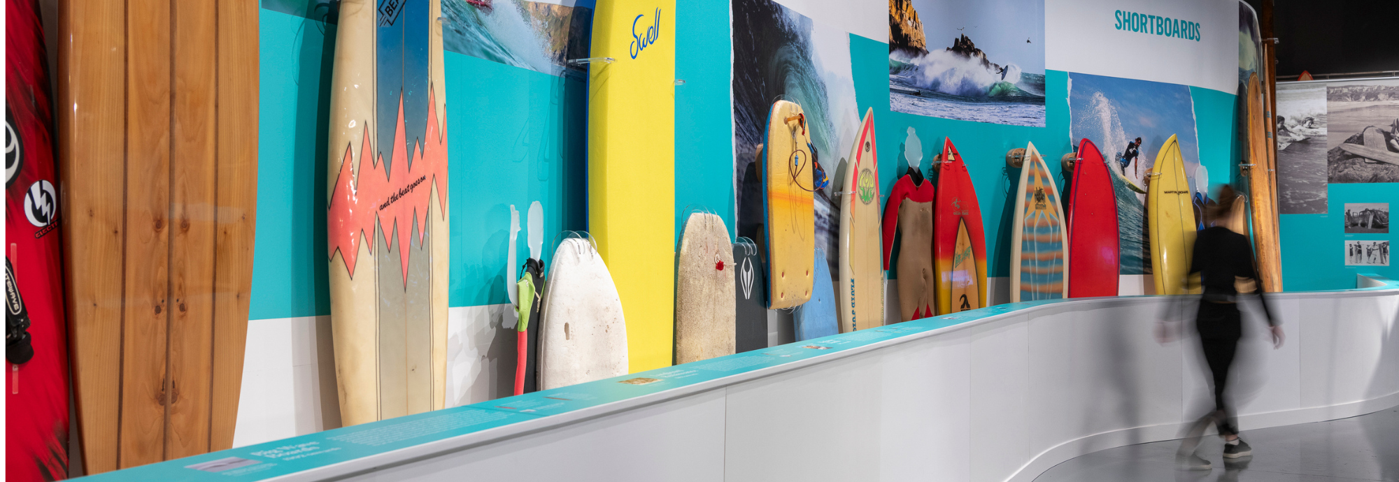 A photograph of an exhibition display of colourful surfboards.