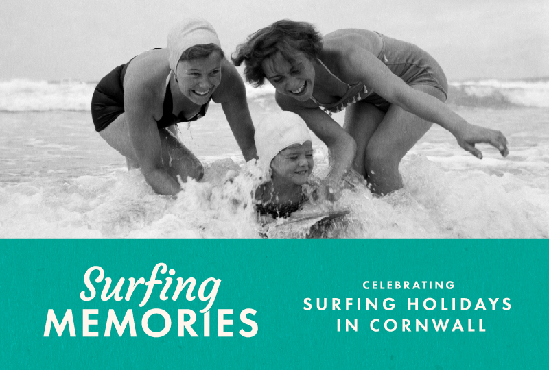 Two women and one child, in vintage swimsuits laugh and play in the surf at the beach; text reads "Surfing Memories, Celebrating Surfing Holidays in Cornwall."