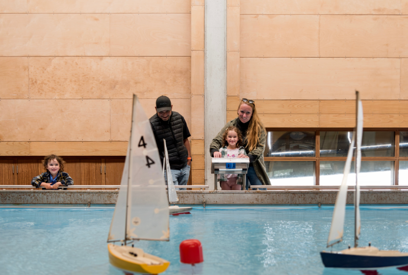 A family with two children enjoying sailing model boats on the Boat Pool at National Maritime Museum Cornwall.