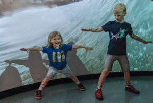 Two Children enjoy the SURF! projection wall at National Maritime Museum Cornwall.