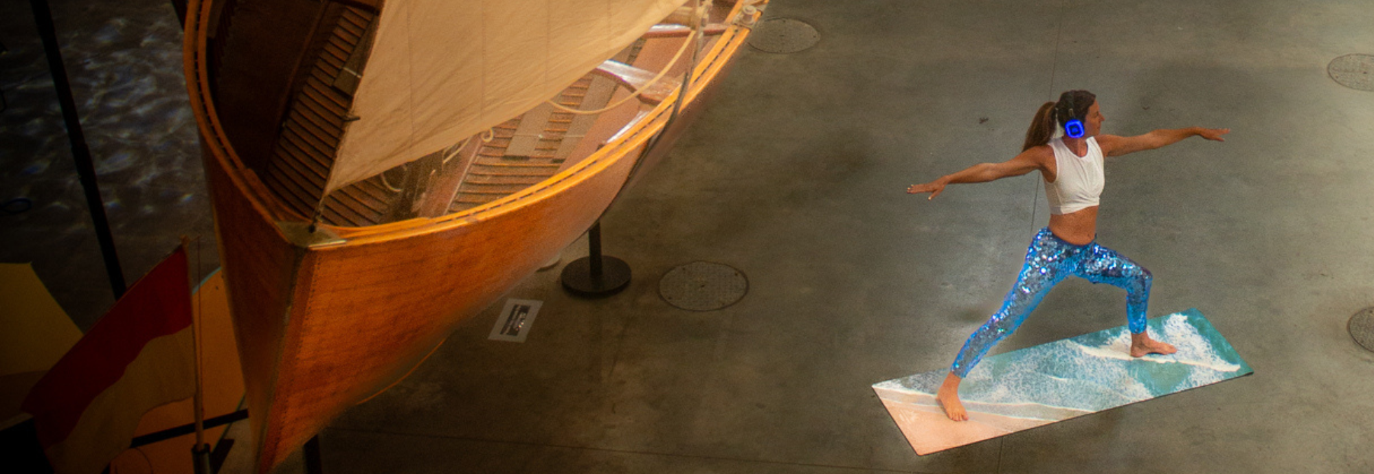 A woman stands in a yoga pose in the National Maritime Museum Cornwall Boat Hall