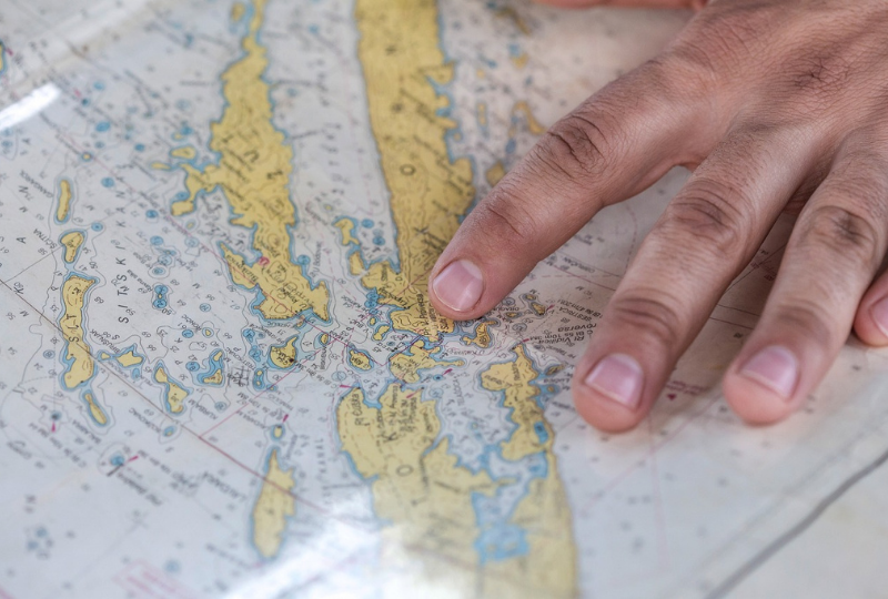 A close-up of a person's hands pointing at an Admiralty Chart.