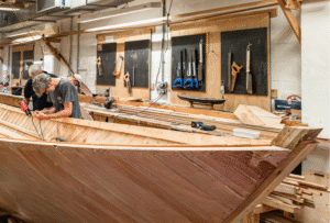 Members of the boatbuilding team working on the Helford SOE boat replica build in the boatbuilding workshop at National Maritime Museum Cornwall.