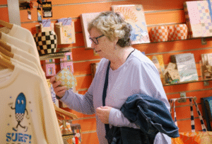 A woman holds up a candle product to take a closer look in National Maritime Museum Cornwall Gift Shop.
