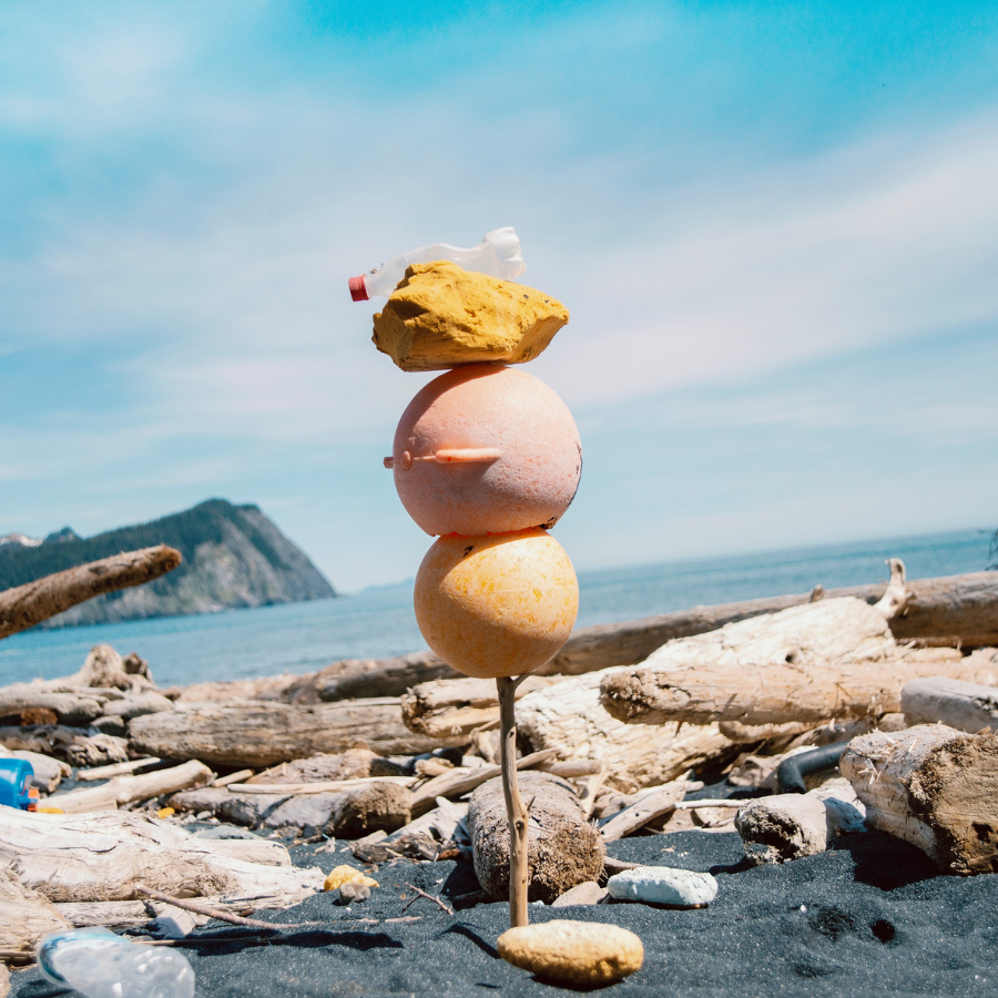 Gore Point Beach Alaska, 2013 A photographic artwork by Andy Hughes show plastic flotsam and jetsam stacked vertically on a stake of driftwood with a dramatic ocean landscape in the background.