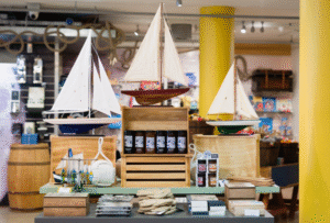 A shop display at National Maritime Museum Cornwall showing three model boats and other nautical products.