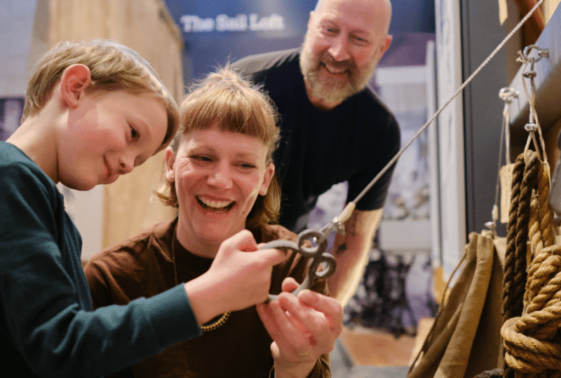 A family explore fishing paraphernalia, ropes, hooks, pulleys etc. in the Cornish Quayside Gallery at National Maritime Museum Cornwall.