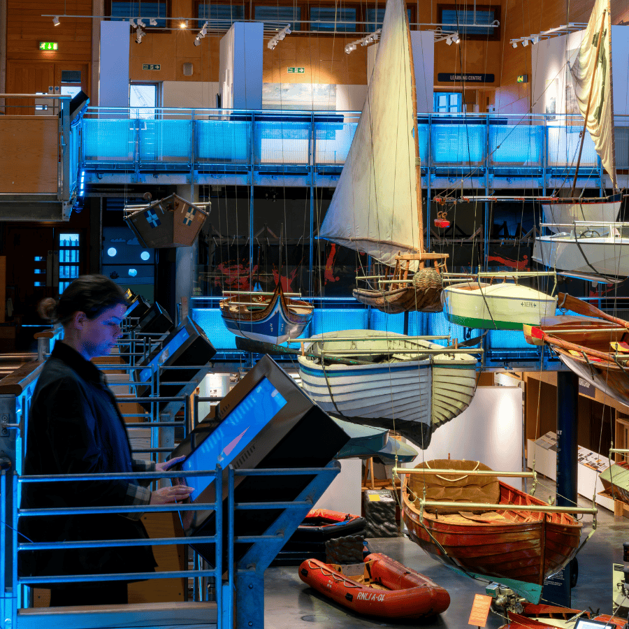 A visitor looks at an interactive screen as they explore the Boat Hall at National Maritime Museum Cornwall