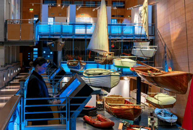 A visitor looks at an interactive screen as they explore the Boat Hall at National Maritime Museum Cornwall