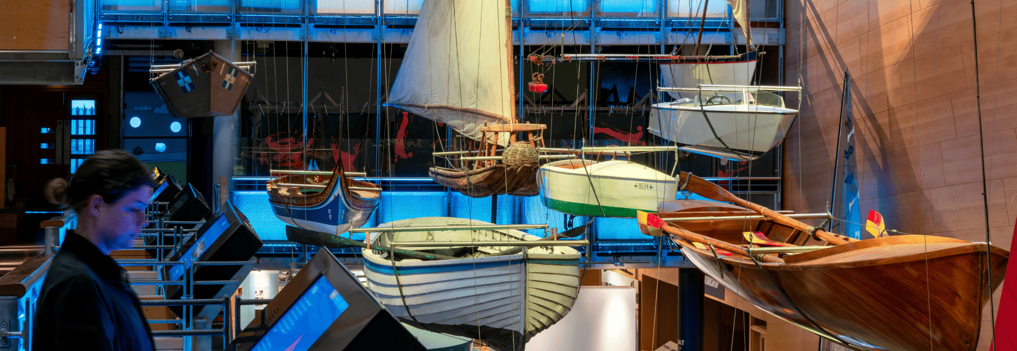 A visitor looks at an interactive screen as they explore the Boat Hall at National Maritime Museum Cornwall