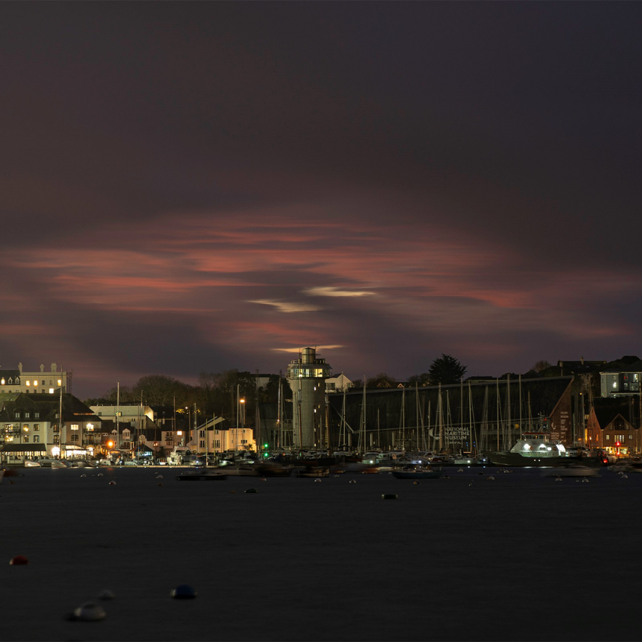 The Lookout Tower and Museum building in Falmouth Harbour under a cloudy pink twilight sky.