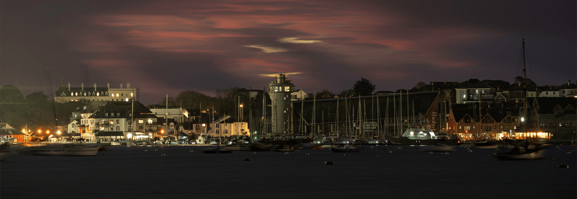 The Lookout Tower and Museum building in Falmouth Harbour under a cloudy pink twilight sky.