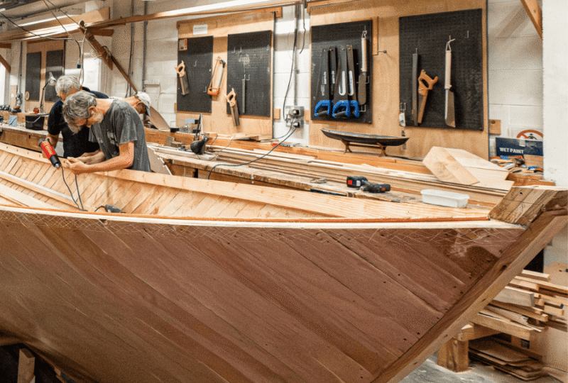 Two men working on a wooden boatbuilding project in the boatbuilding workshop at National Maritime Museum Cornwall.
