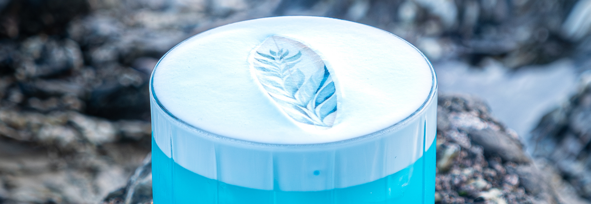 A bright blue cocktail drink with a decorative surfboard design.