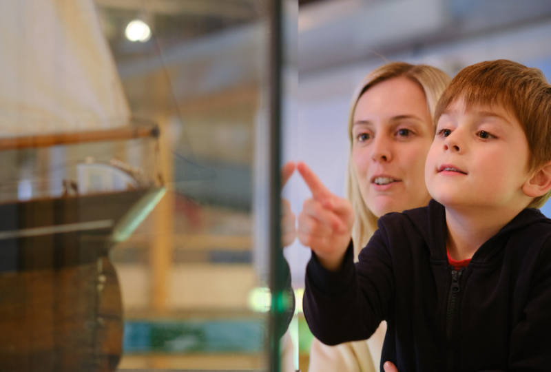 Family pointing at Museum objects in display case at NMMC