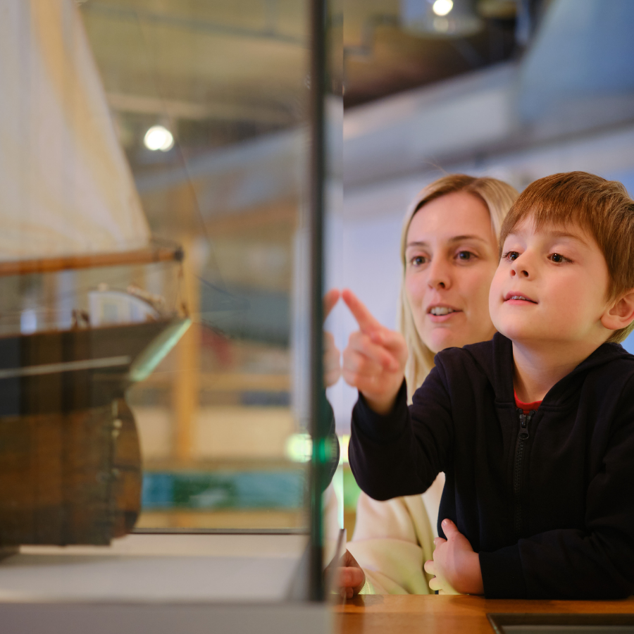 Family pointing at Museum objects in display case at NMMC