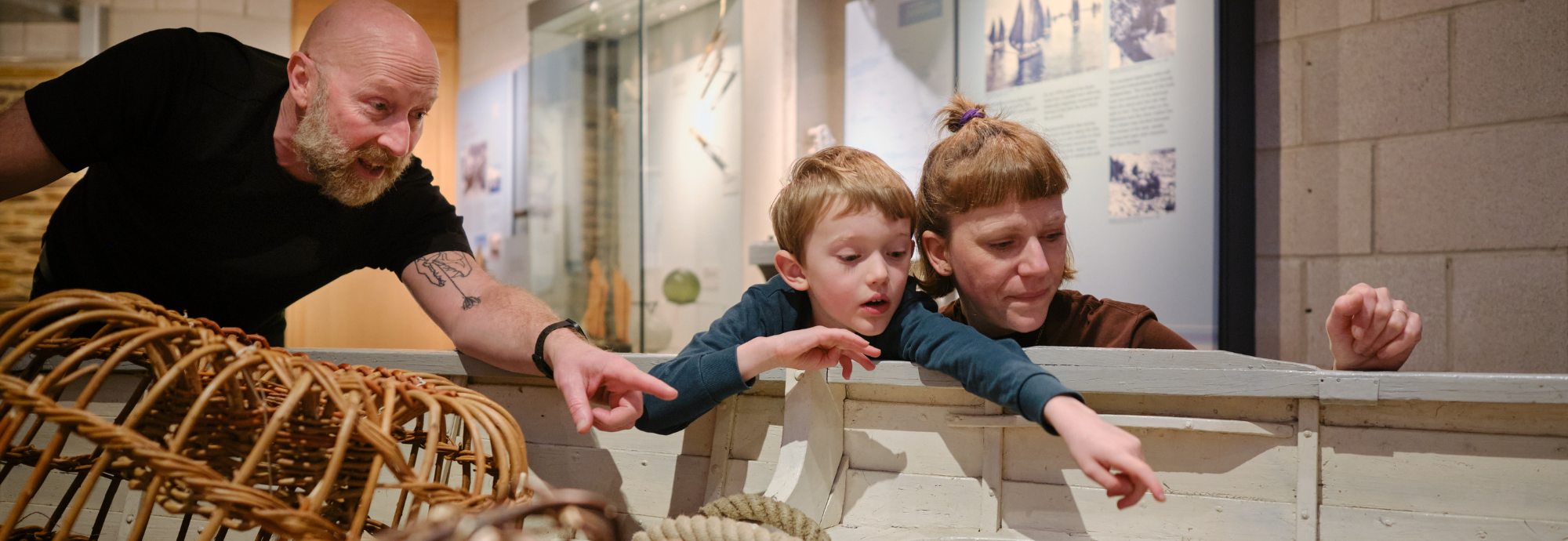 Family pointing at Museum lobster pots at NMMC