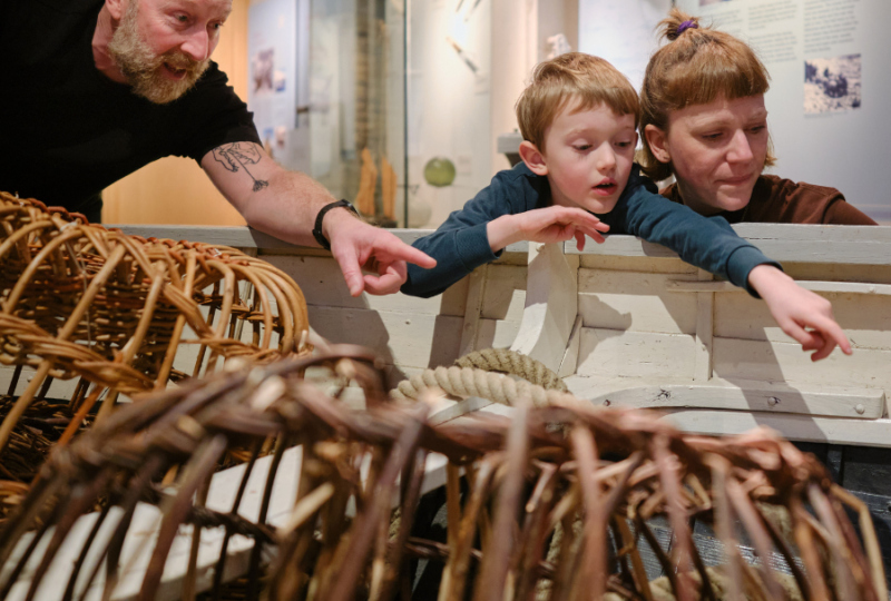 Family pointing at Museum lobster pots at NMMC