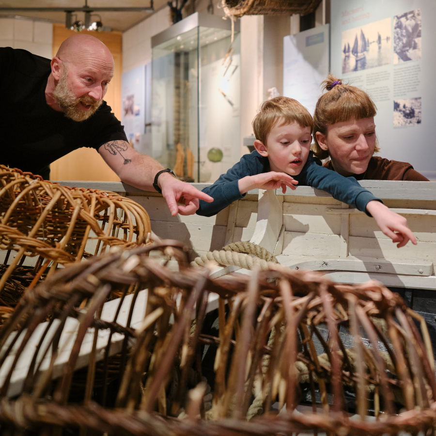 Family pointing at Museum lobster pots at NMMC