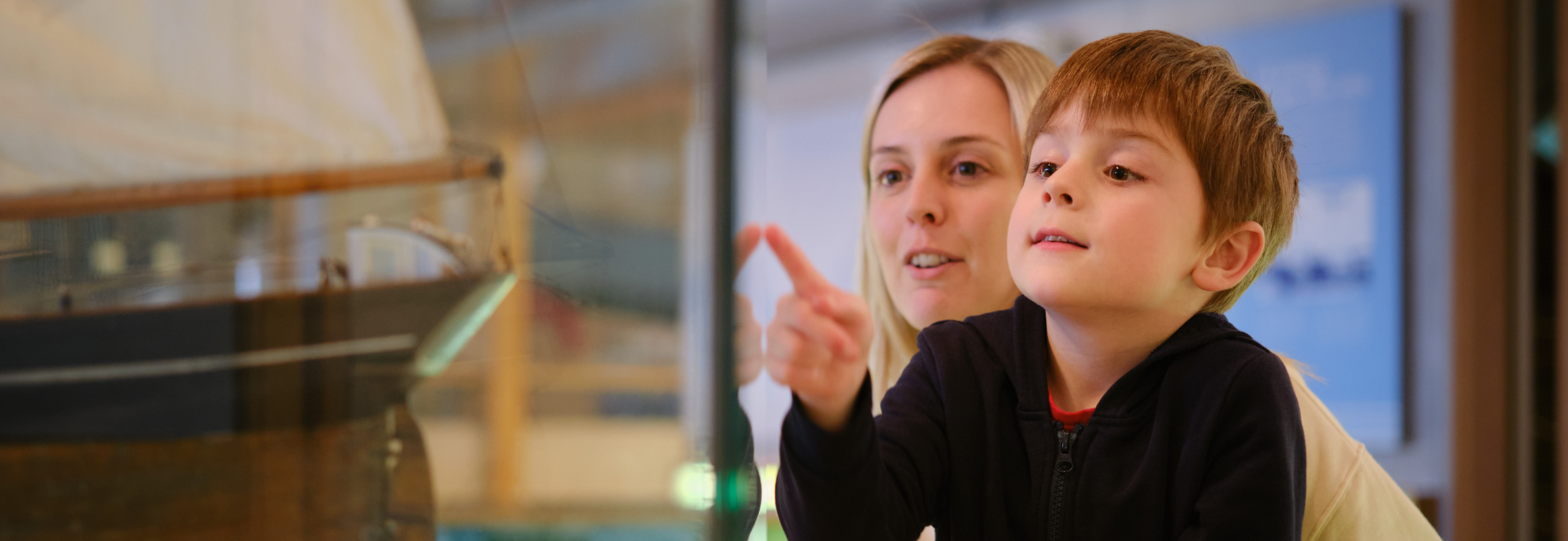 Family pointing at Museum objects in display case at NMMC