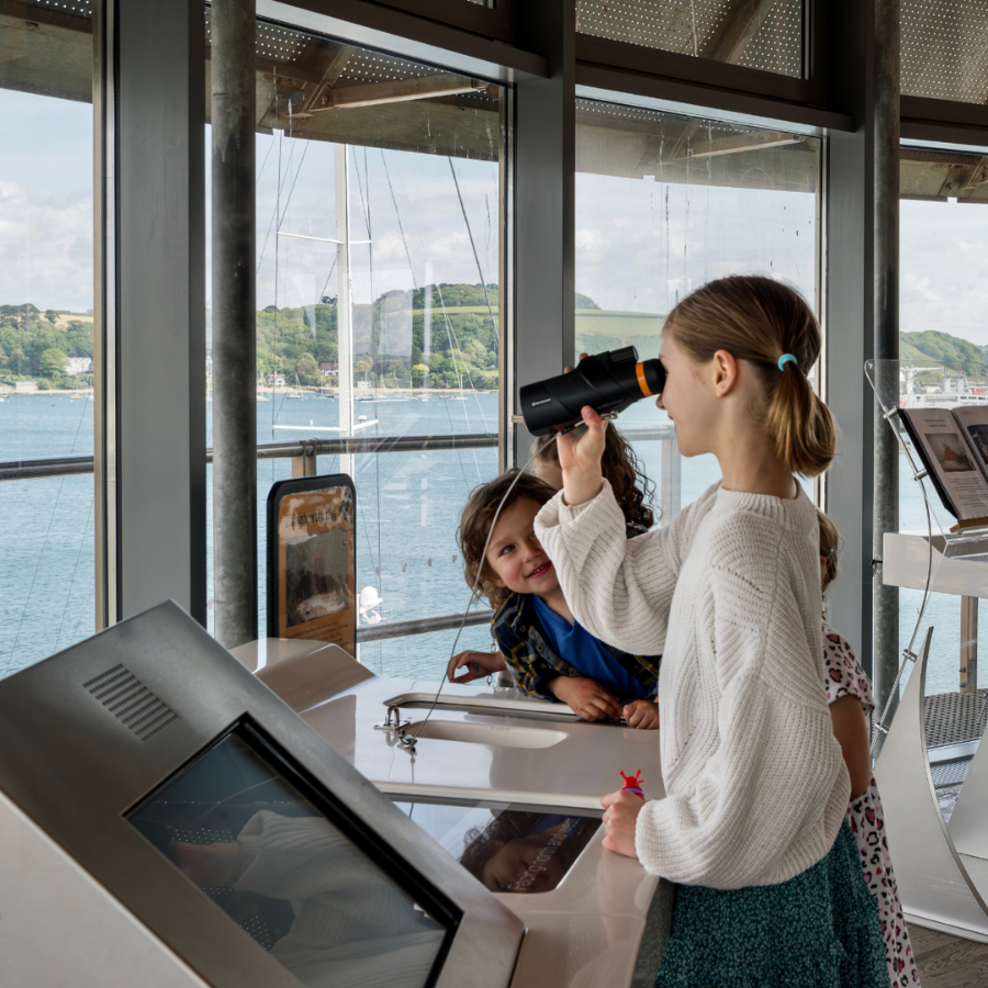 Children look through handheld telescopes to admire the view in The Lookout at National Maritime Museum Cornwall