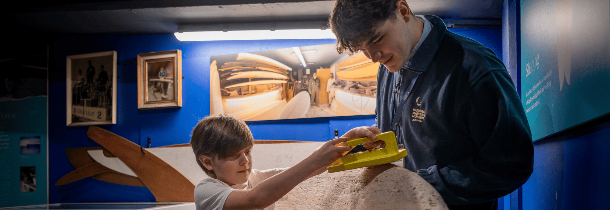 A Museum Volunteer helps a young visitor in SURF! Exhibition