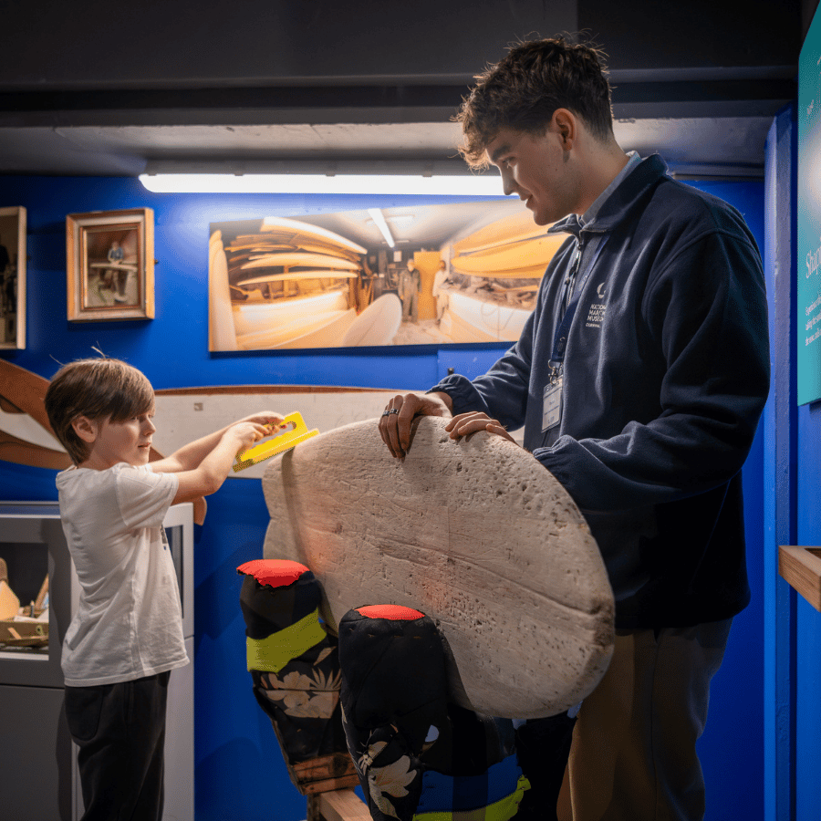 A Museum Volunteer helps a young visitor in SURF! Exhibition
