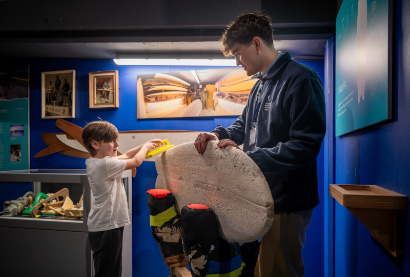 A Museum Volunteer helps a young visitor in SURF! Exhibition